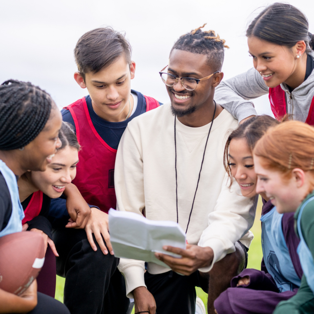 Male sports teaching assistant with group of young kids