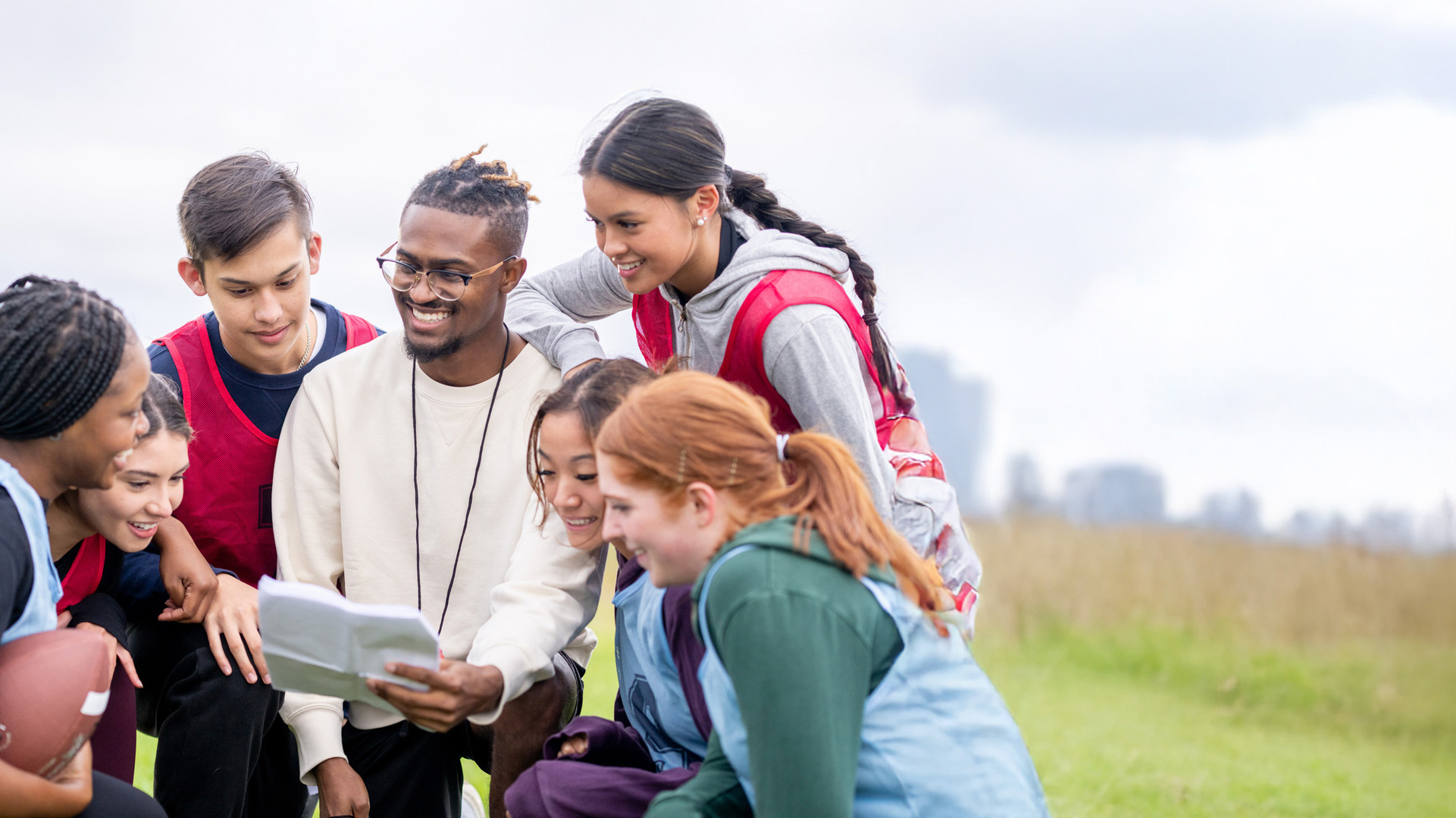 Male sports teaching assistant with students in school field
