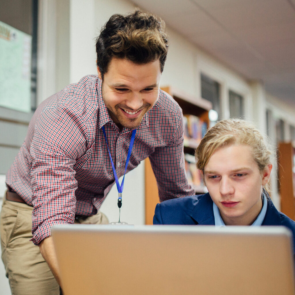 Male teaching assistant working with pupils in a high school