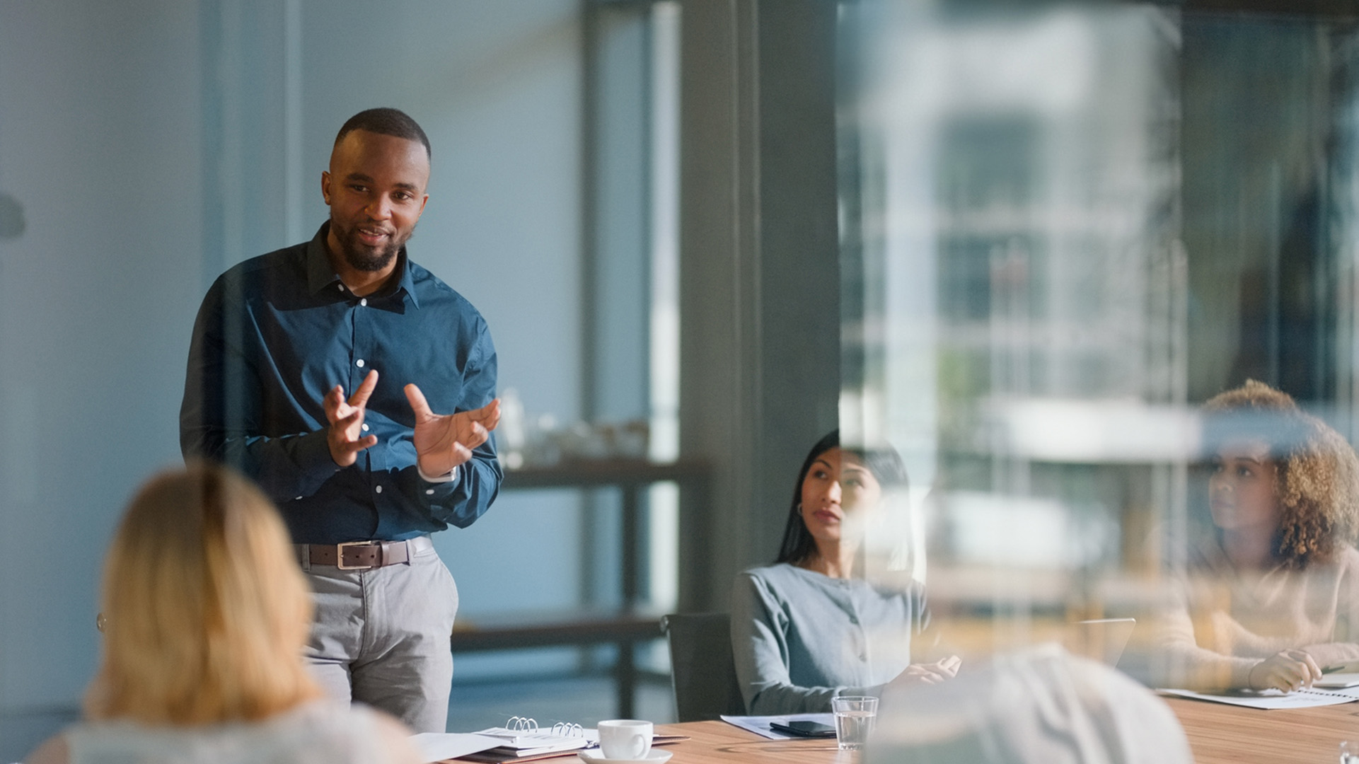 Male speaking to staff members in a boardroom setting