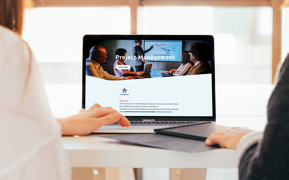A tutor and student working on a project management course on a laptop