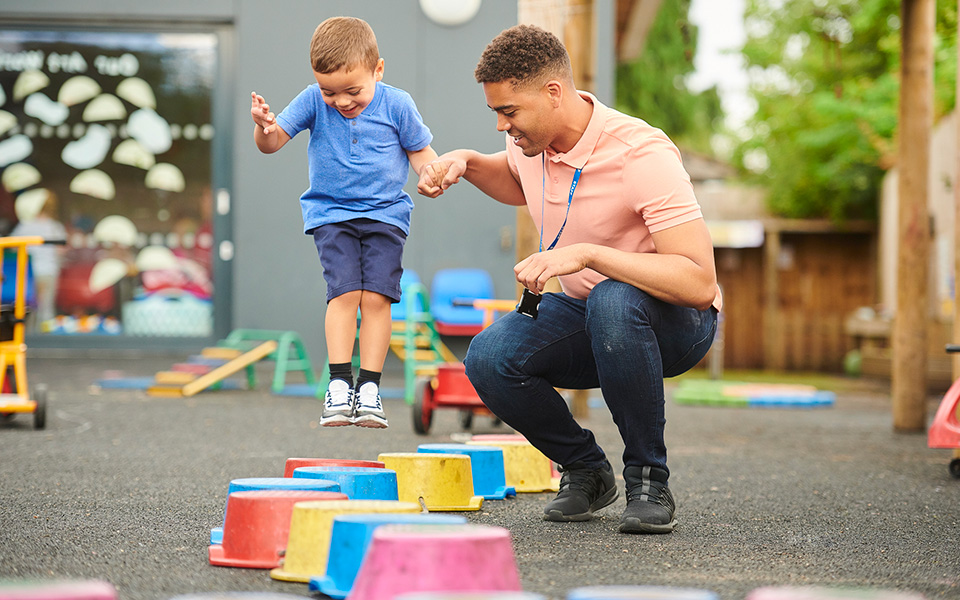 Boy playing outside with early years worker