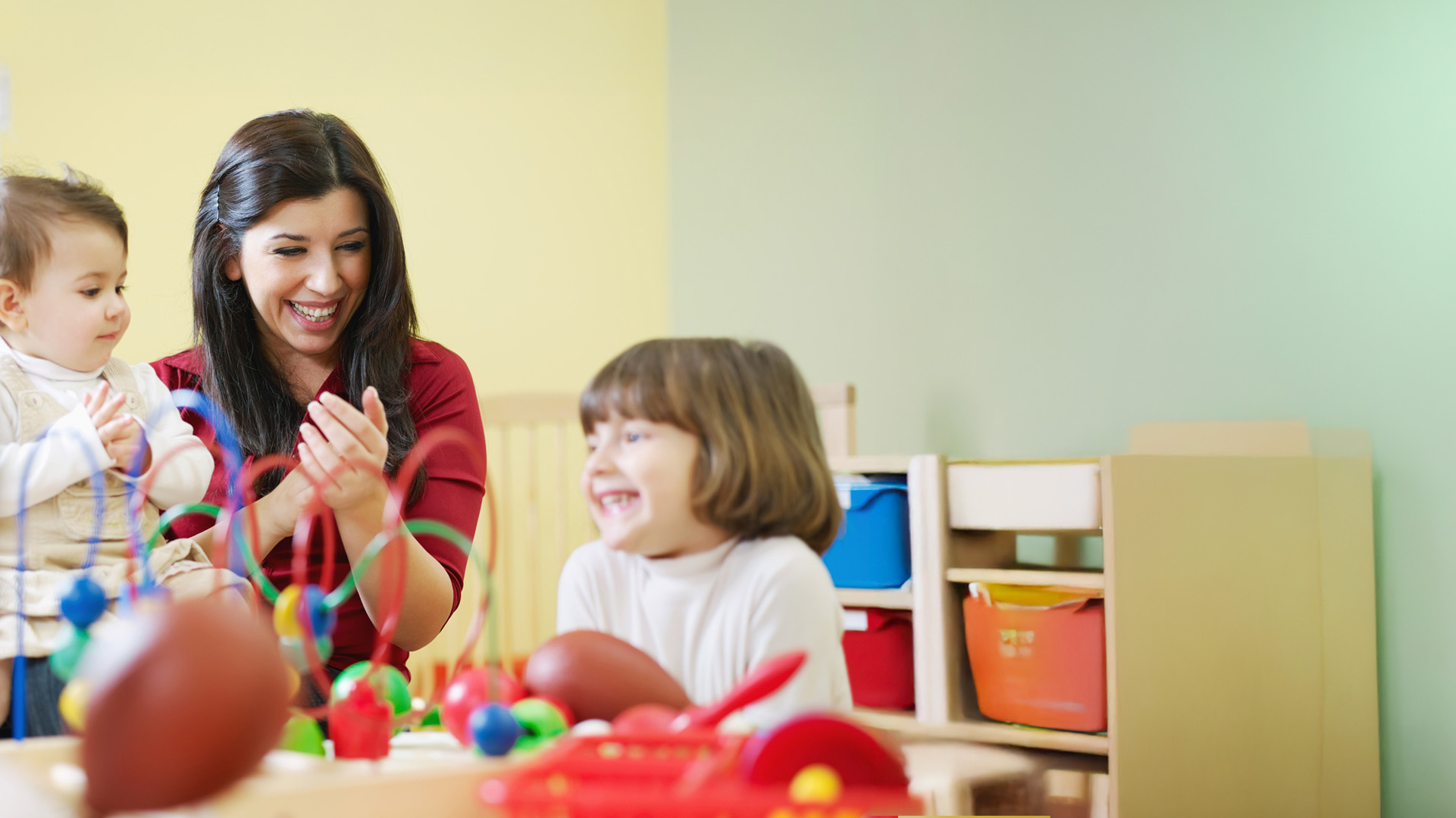 Happy female nursery worker with early years children
