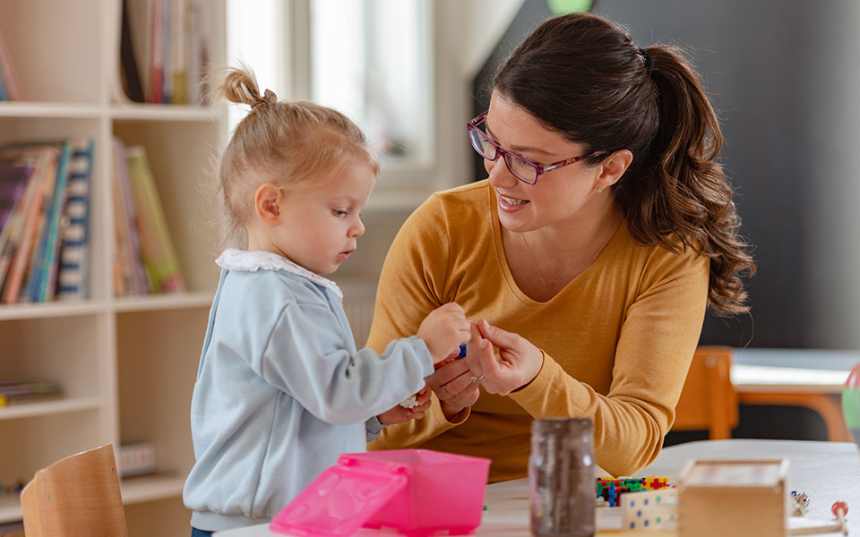 Female nursery worker engaging with small child