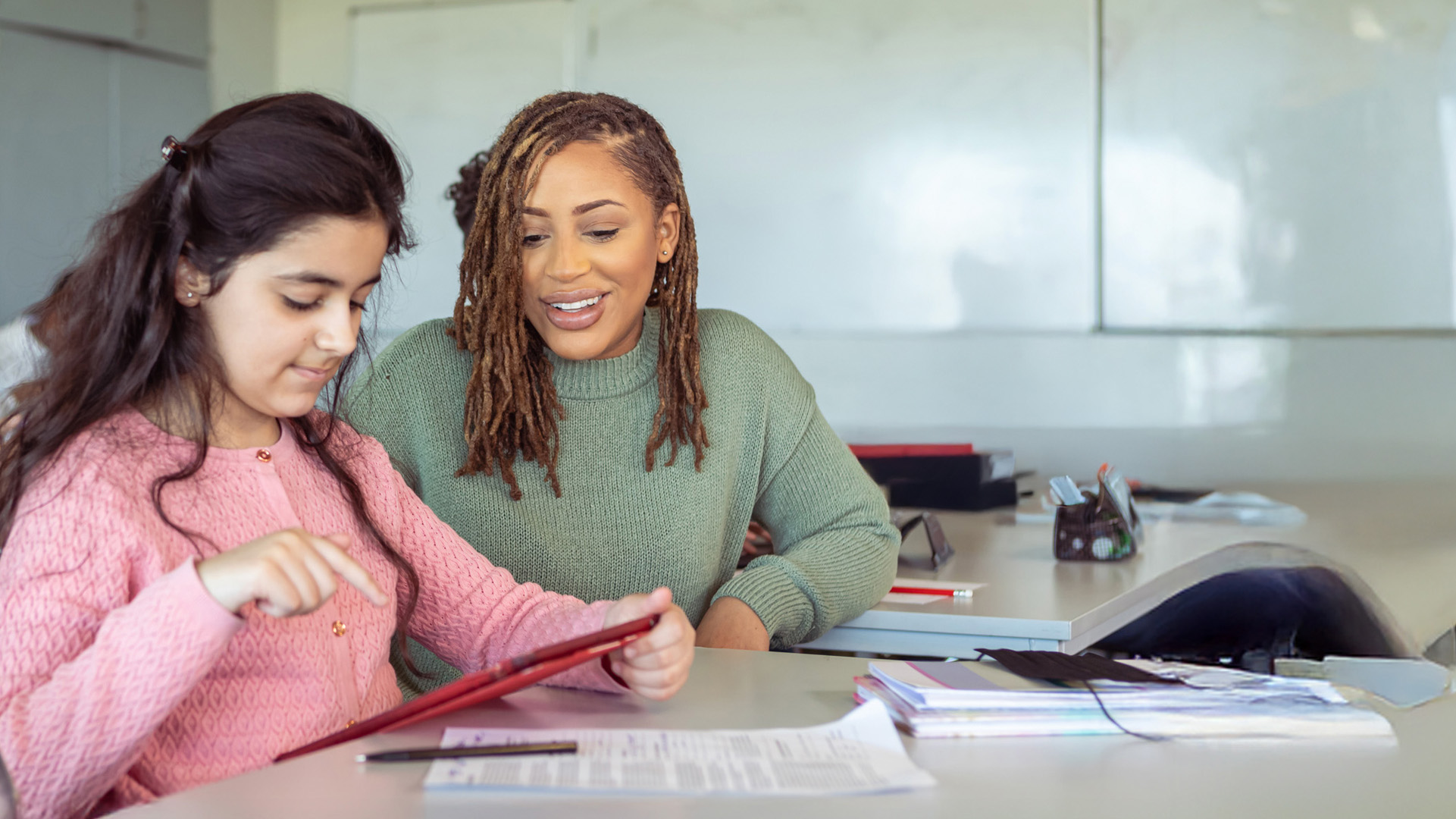 Female teaching assistant working with school pupil