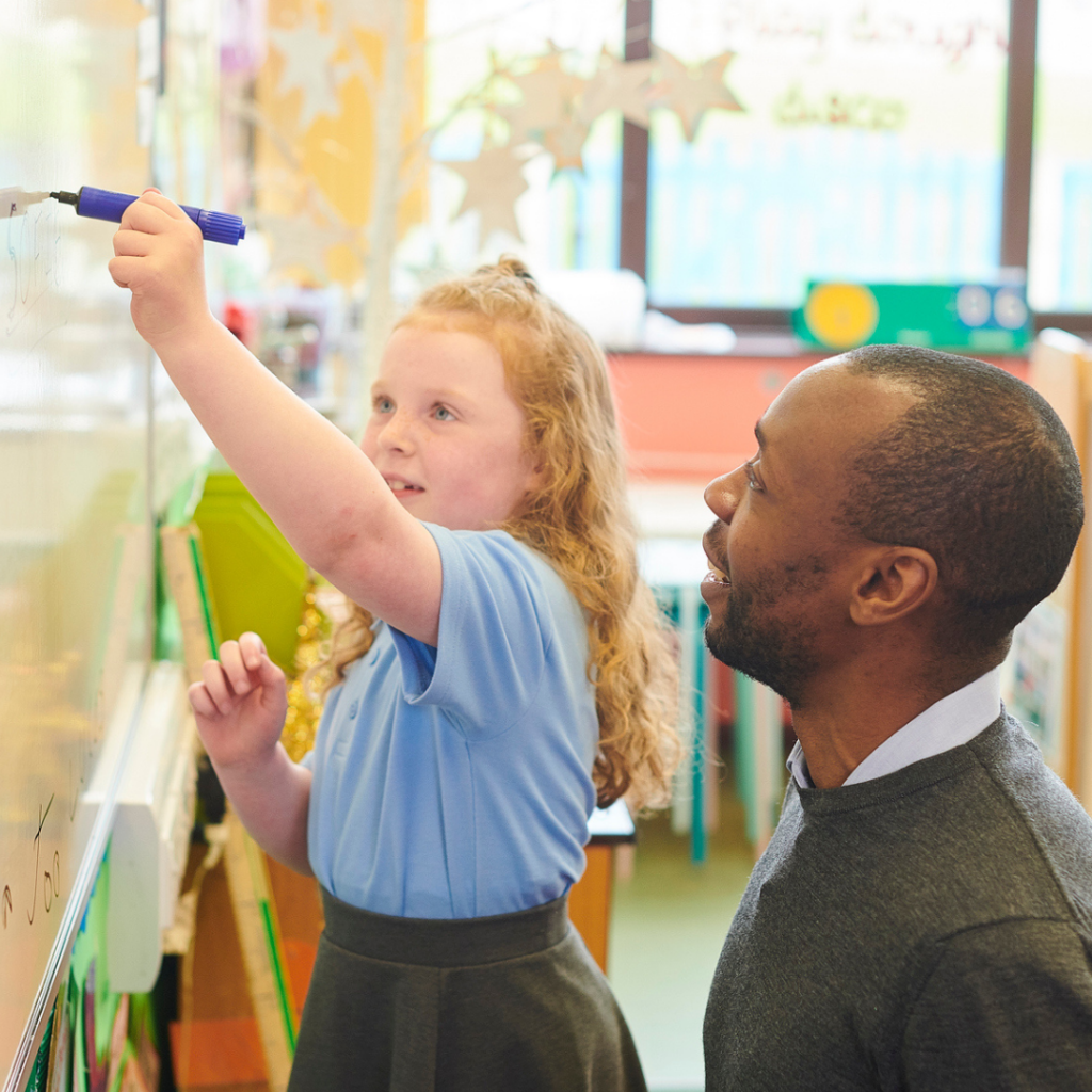 Male teaching assistant with young child in classroom