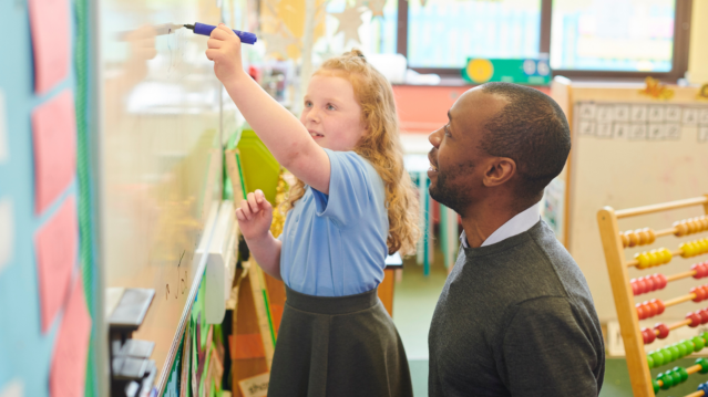 Male teacher with young school pupil