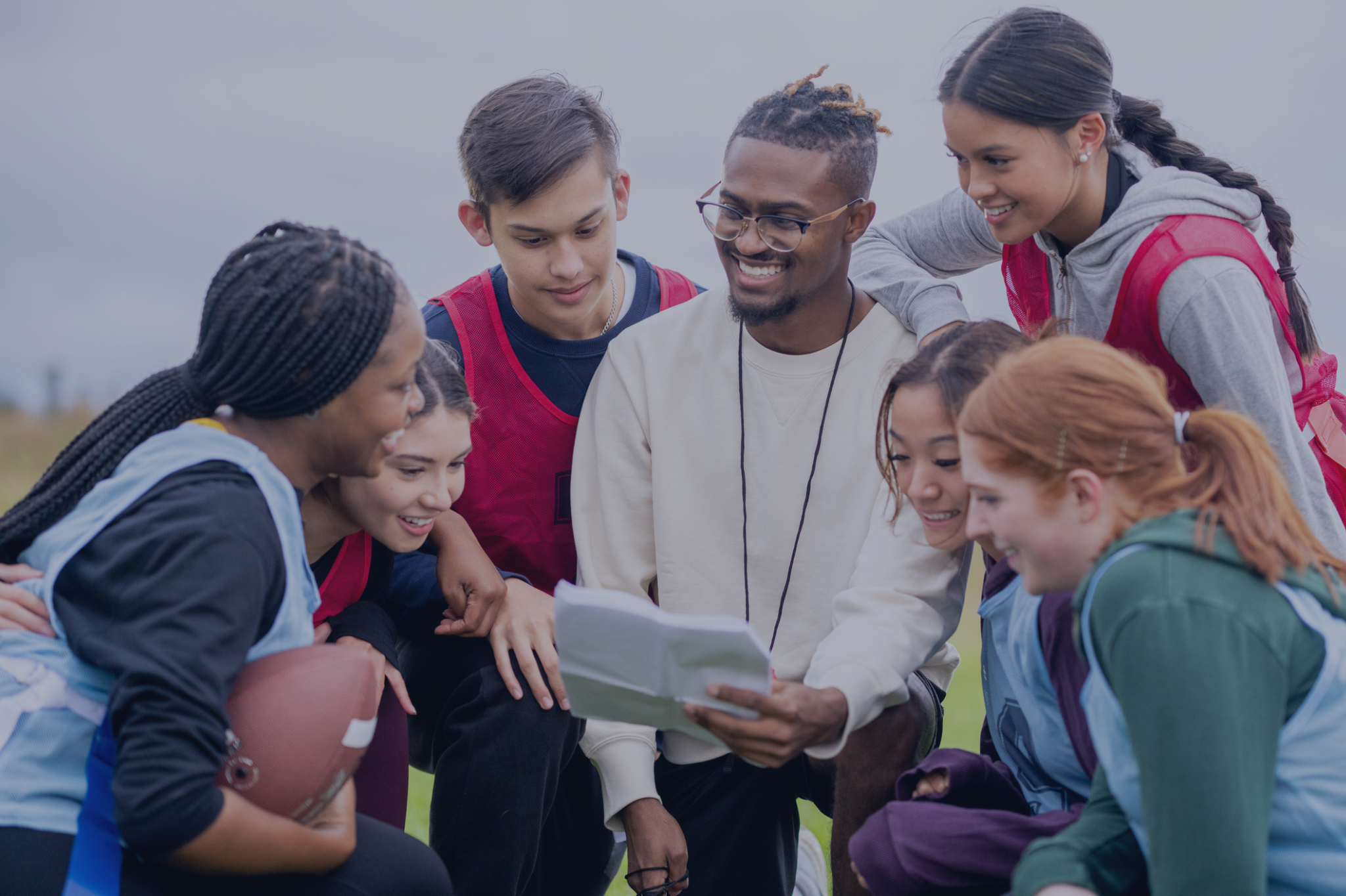 A group of kids wearing sports gear huddled around an instructor.