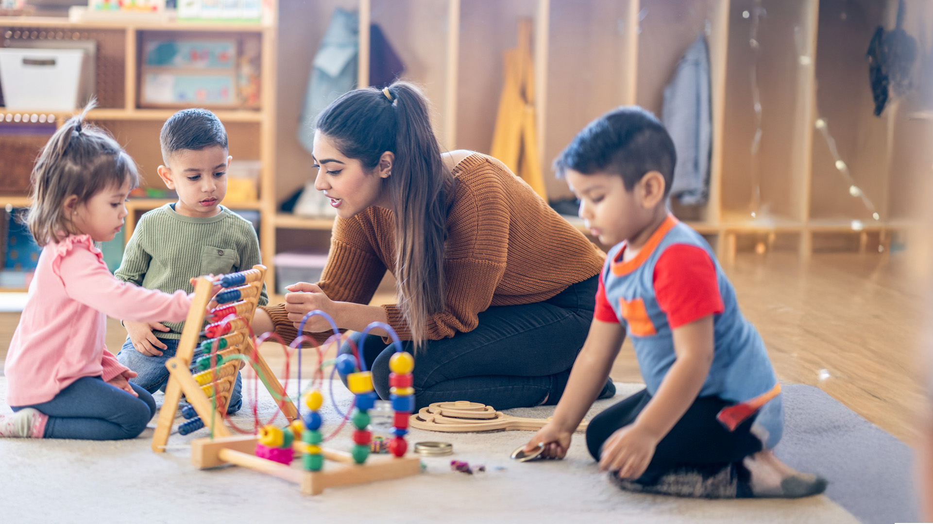 Female early years practitioner with children in a nursery setting