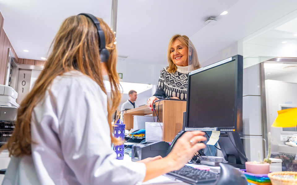 Young female talking to woman at medical reception desk