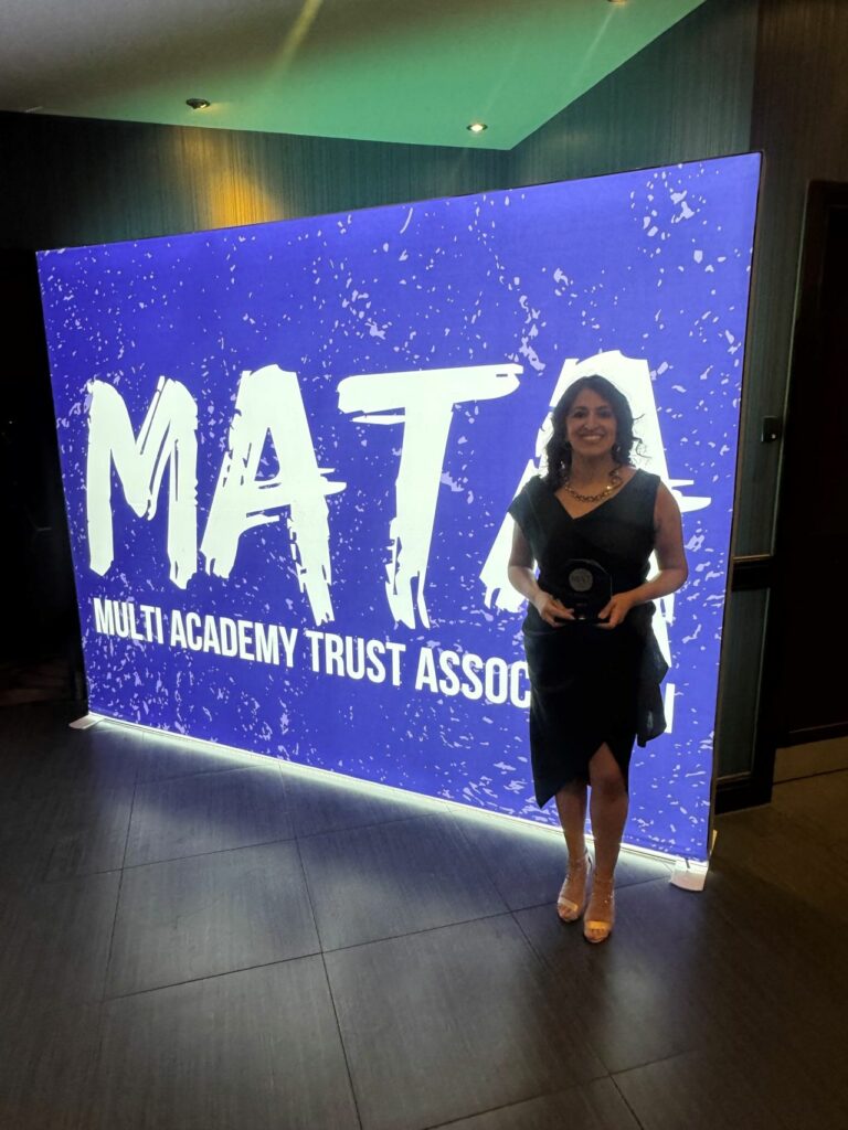 Amy Lalla standing in front of a MATA backdrop holding the award.