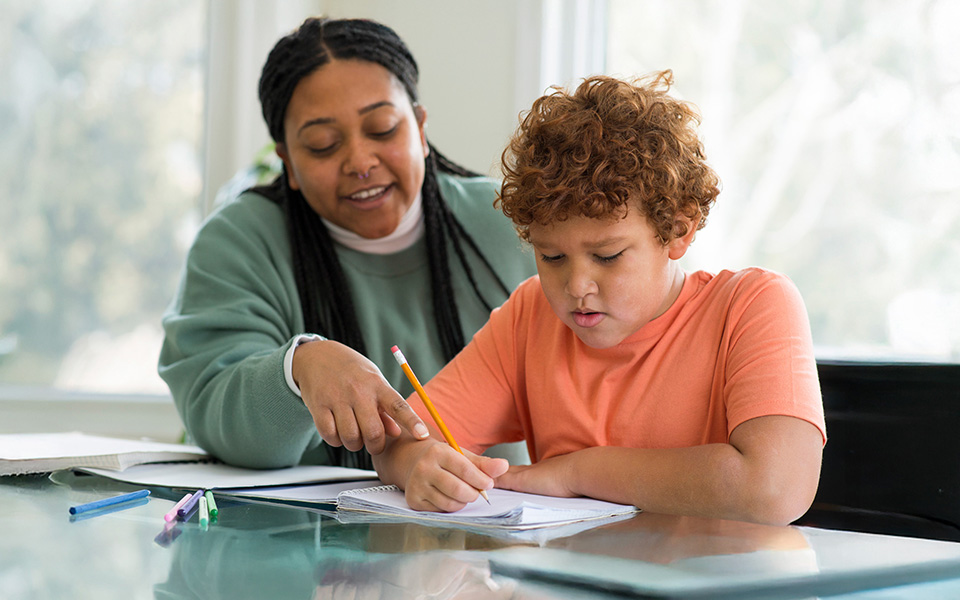 Female teaching assistant helping a boy with homework