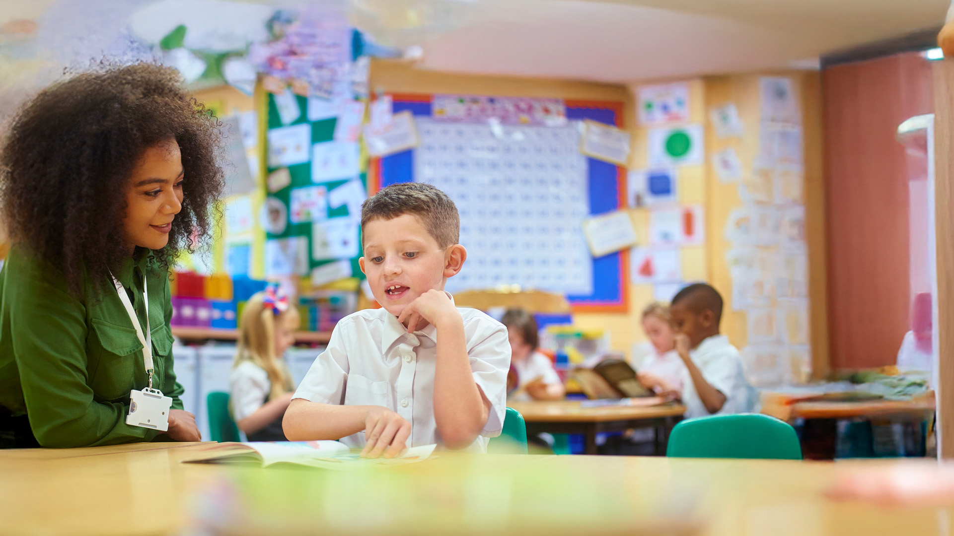 Female teaching assistant working in a primary school classroom